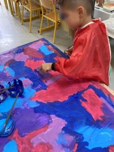 Un enfant peint un fond cyan violet et magenta